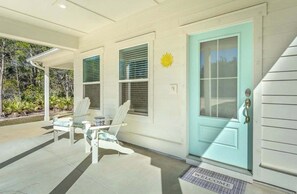 A house with a covered porch, a blue door, and a welcome mat.