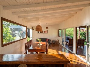 Un comedor espacioso con una mesa y sillas de madera, ventanas amplias y vistas a zonas verdes.