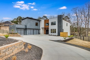 A modern two-story house with a garage, a driveway, and landscaped gardens. - Serenity Estates in South Fulton (Atlanta)