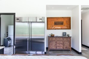 A modern kitchen with a stainless steel refrigerator, wooden cabinetry, and a welcome sign on the wall. - 3-bedroom vacation home on Merritt's Mill Pond in Marianna with yard and dock. (Marianna)