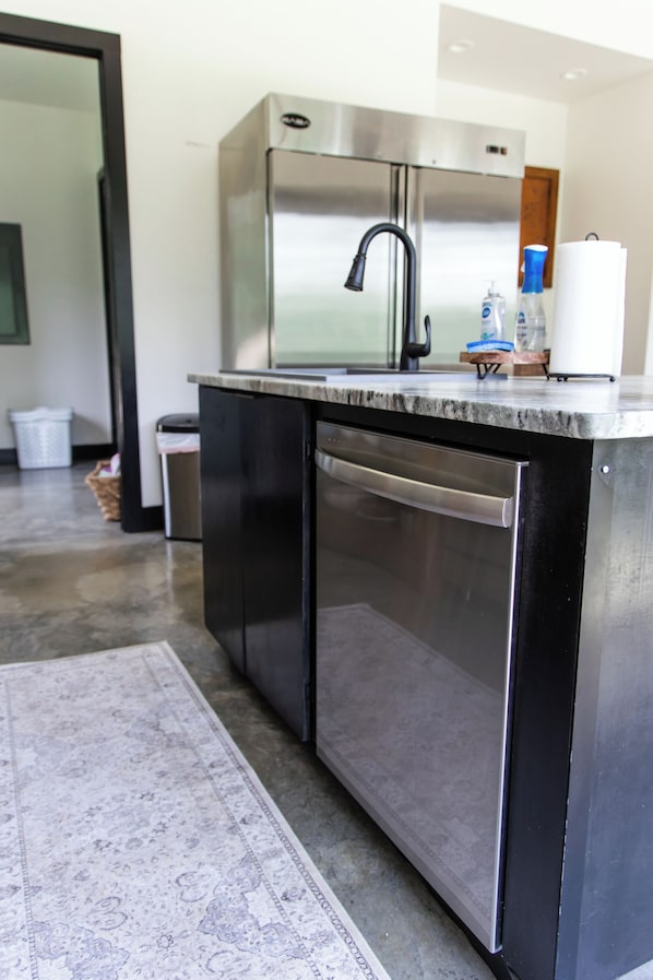 Una cocina moderna con electrodomésticos de acero inoxidable, una encimera negra y un lavavajillas integrado.