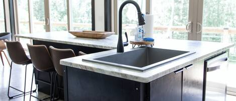 A modern kitchen with a black countertop, a sink, and a bar stool.