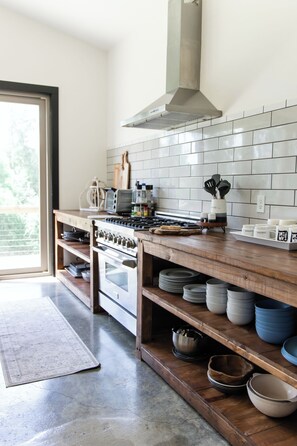 Una cocina moderna con estufa a gas, horno y salpicadero de azulejos blancos.