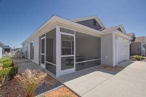 Einbungalow mit überdachter Terrasse, Garage und kleinem Garten.