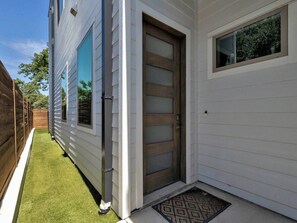 A house with a wooden door, a window, and a small porch area. - Entire Duplex Unit · Cozy, Bright & Fully Equipped (Dallas)