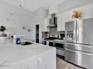 A modern kitchen with a large island, stainless steel appliances, and a backsplash. - Entire Duplex Unit · Cozy, Bright & Fully Equipped (Dallas)