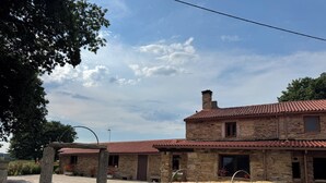 A stone building with a red-tiled roof, multiple windows, and a stone bench in front.