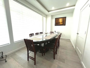 A conference room with a round table, chairs, and a painting on the wall. - Modern 6BR Home - Ideal for Quiet Family Holidays (Vancouver)