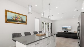 A modern kitchen with a central island, white cabinetry, and pendant lighting. - Modern 6BR Home - Ideal for Quiet Family Holidays (Vancouver)