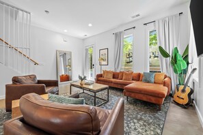 Ein modernes Wohnzimmer mit Ledersofas, einem Couchtisch und einer Gitarre.
