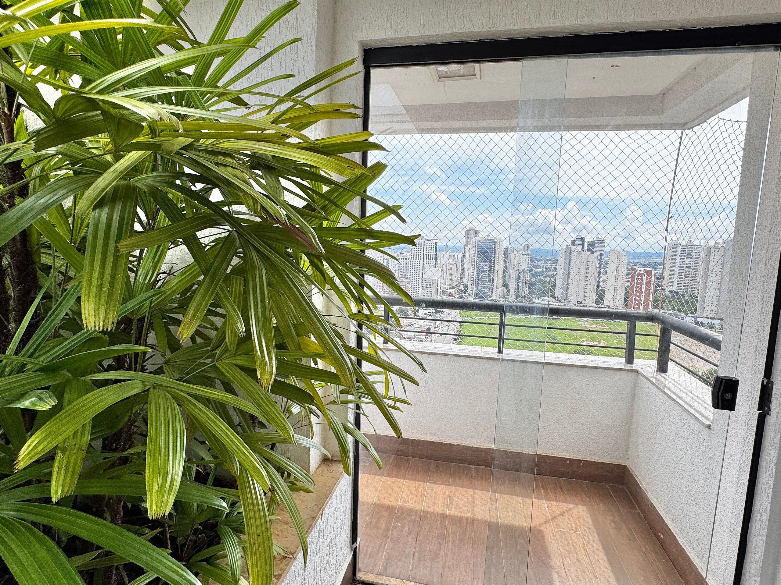 Un balcon avec vue sur la ville, une plante en pot et une porte donnant sur un espace intérieur.