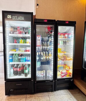 Três máquinas de venda automática com diversas bebidas e lanches.