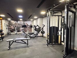Un gimnasio con equipo de ejercicio, una banca y una estructura para sentadillas.