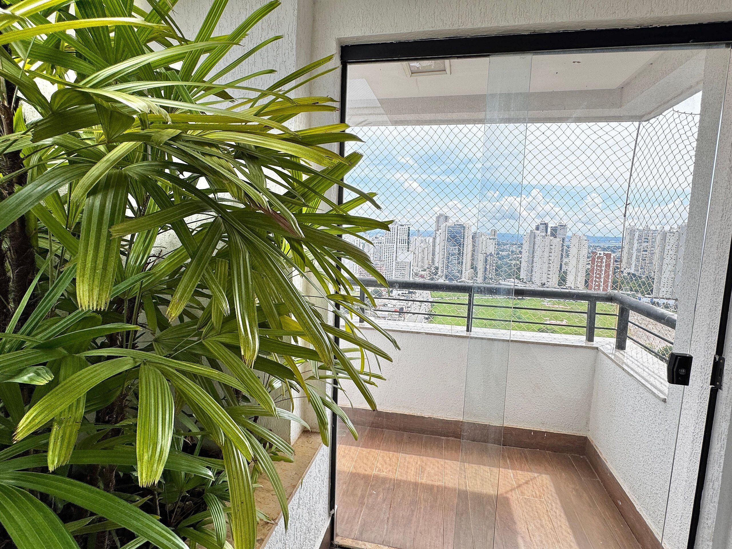 A balcony with a city view, a potted plant, and a door leading to an interior space.