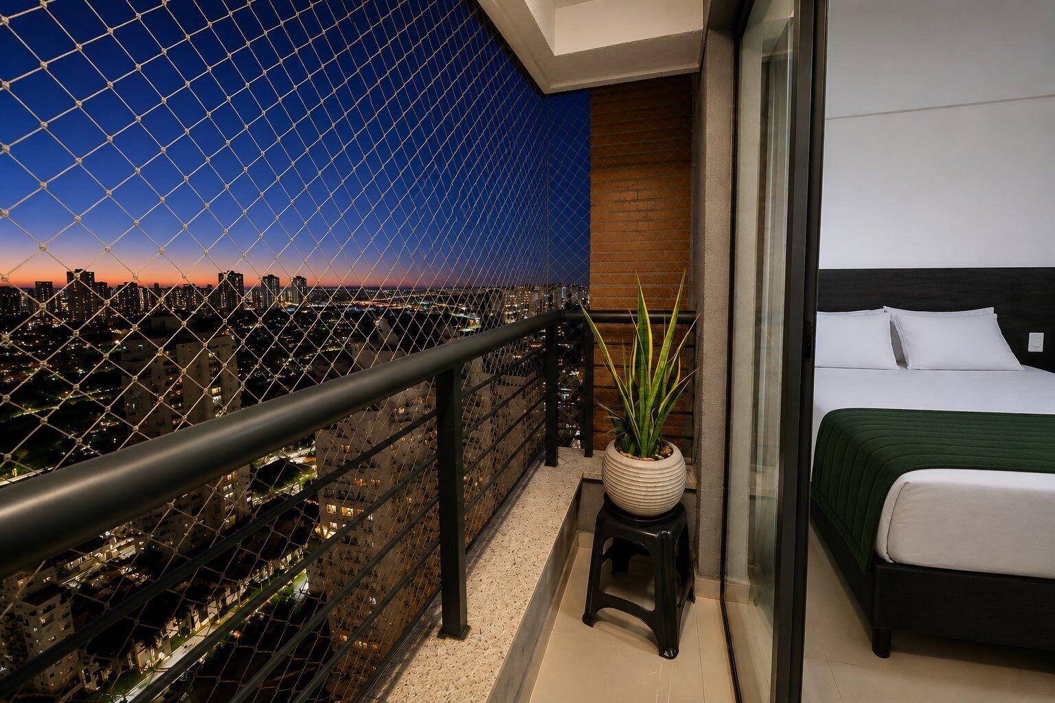 Varanda com vista para a cidade, um vaso de planta e uma cama com colcha verde.