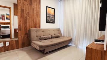 Una sala de estar moderna con un sofá, una pared decorativa de madera, un cuadro enmarcado, un televisor y una ventana con cortinas.