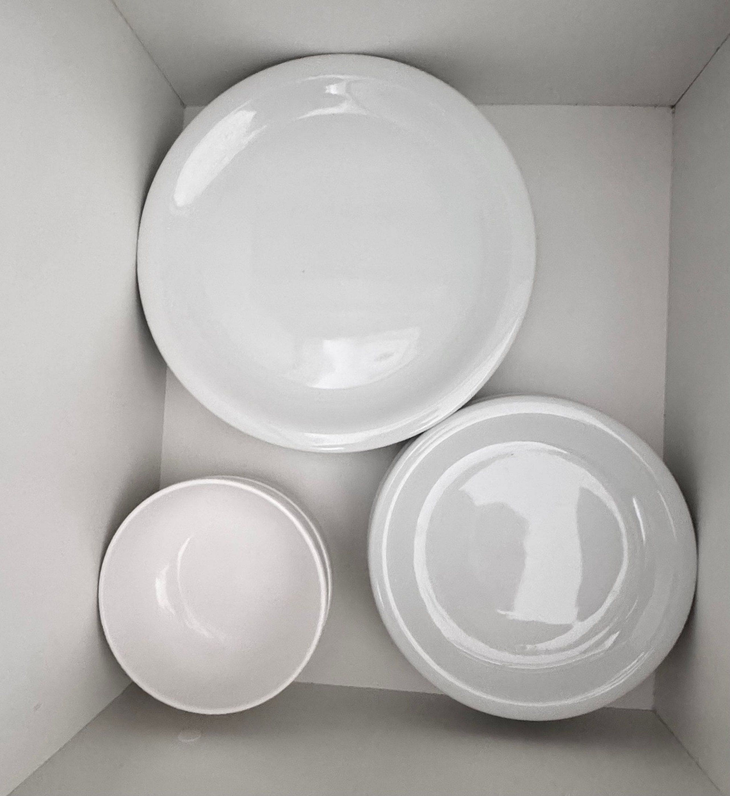 A box containing three white plates of varying sizes.