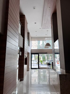 A modern hotel lobby with a glass entrance, wooden paneling, and a clean, reflective floor.
