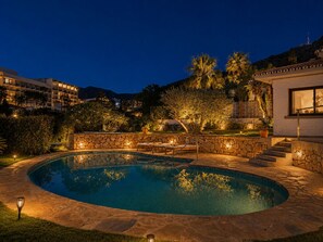 A swimming pool with stone walls and steps, surrounded by greenery and a building with a white facade. - Villa with Private Pool and Mediterranean Gardens (La Capellania)