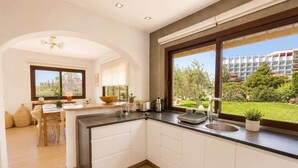 Cozinha moderna com uma janela ampla, área de jantar e vista para um bairro residencial.