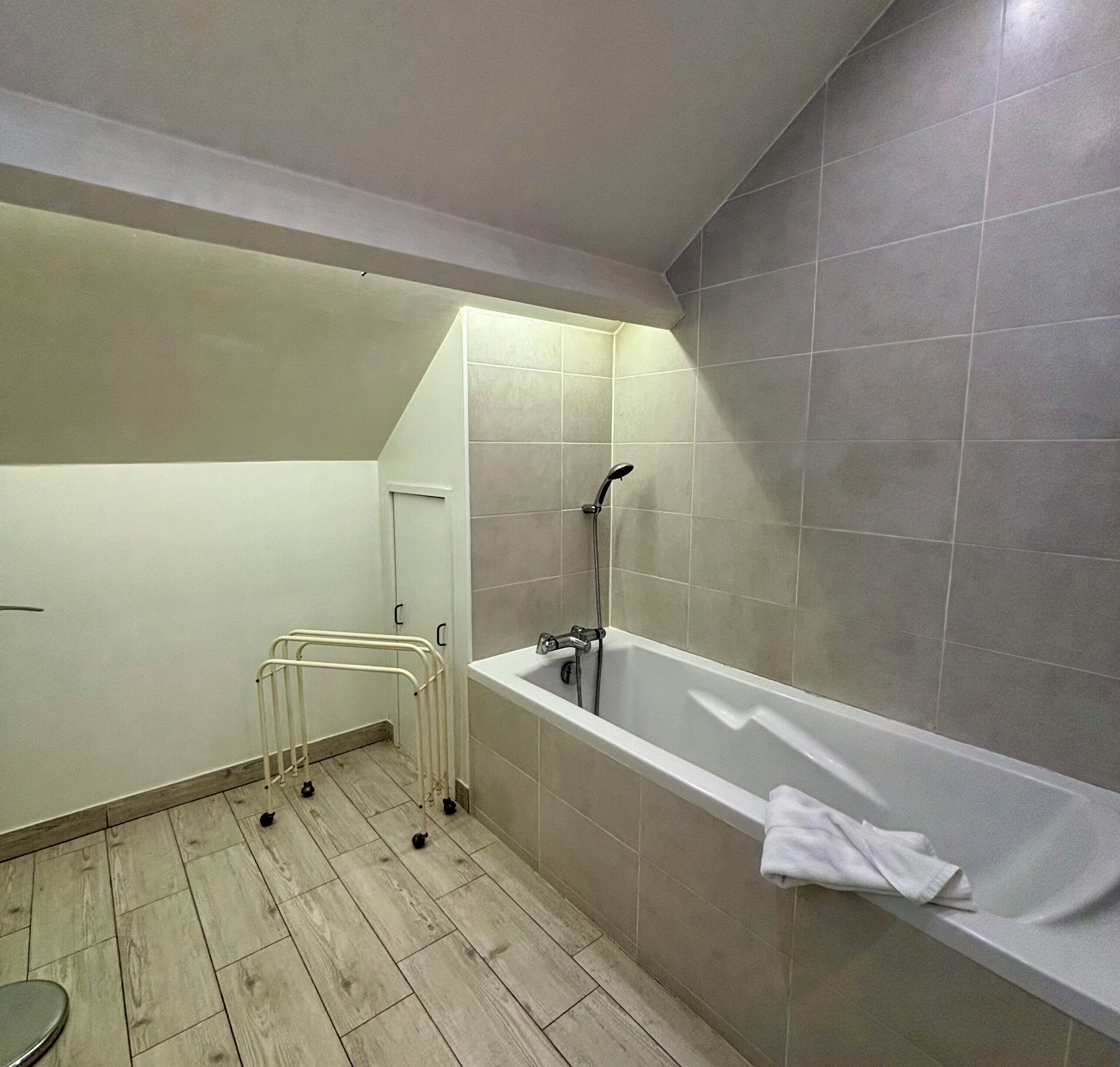 A bathroom with a bathtub, a shower, and a wooden floor.