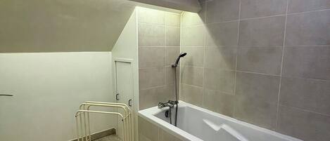 A bathroom with a bathtub, a shower, and a wooden floor.