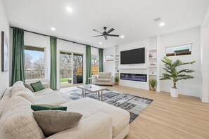Ein modernes Wohnzimmer mit einer Couch, einem Couchtisch, einem Fernseher und einem Kamin.