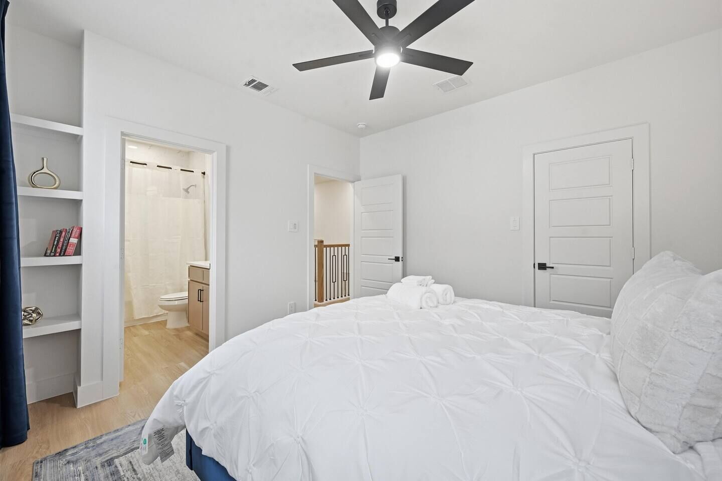 Un dormitorio con cama, ventilador de techo y puerta que da a un baño.