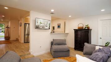 A modern living room with a sofa, ottoman, and a fireplace.