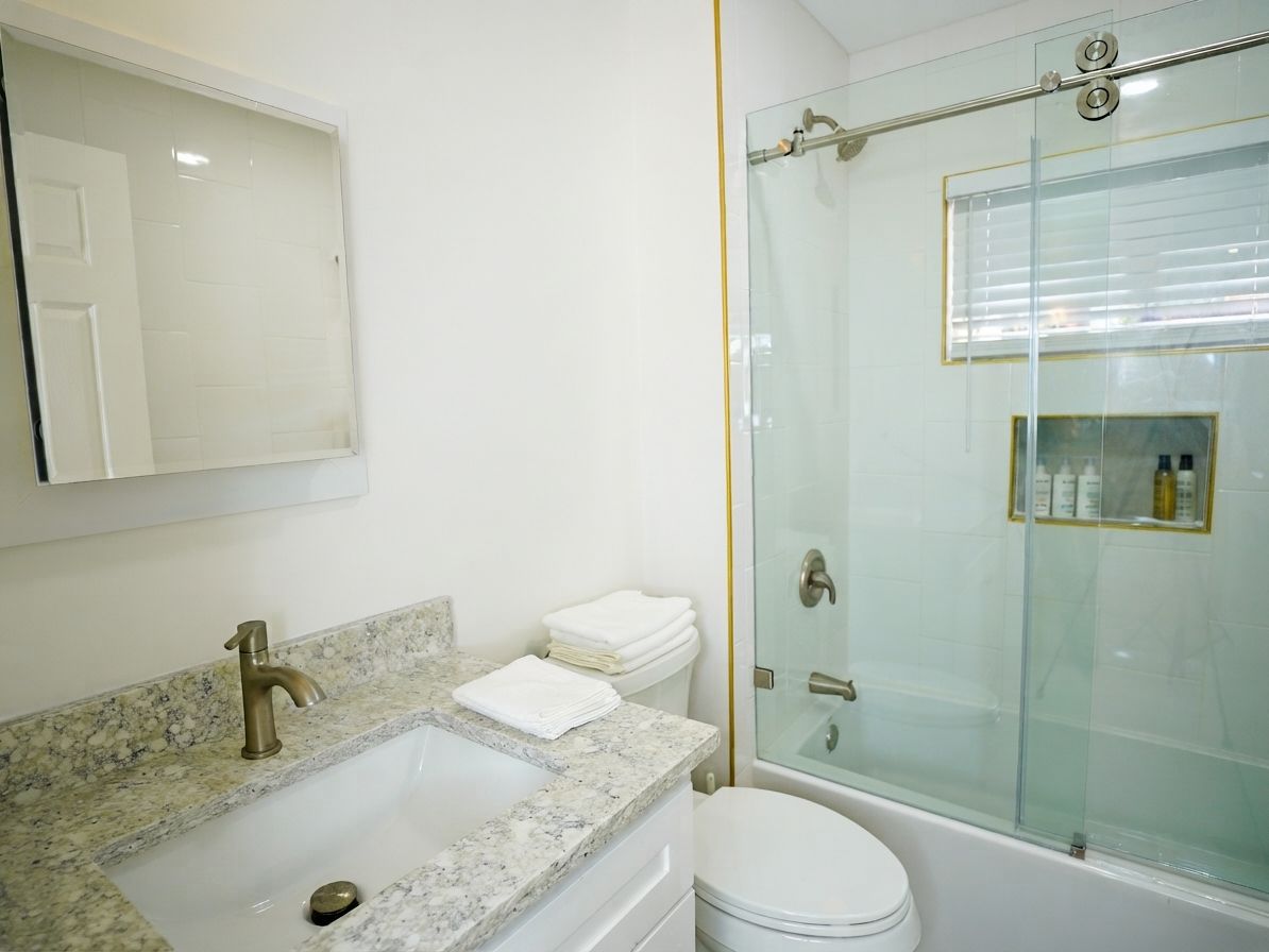 A bathroom with a marble sink, a toilet, and a glass-enclosed shower.