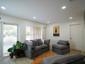 A living room with grey sofas, a large potted plant, a painting, and a wooden floor. - Fully Renovated 4-Bedroom, 3-Bath Home in the Heart of Austin's Attractions (Austin)