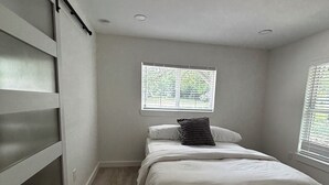 A bedroom with a bed, a window, a door, and a light fixture. - Fully Renovated 4-Bedroom, 3-Bath Home in the Heart of Austin's Attractions (Austin)
