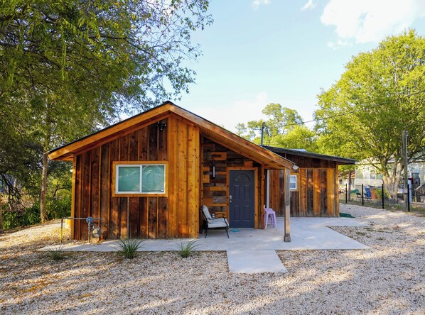 A wooden cabin with a large window, a door, and a small porch area.