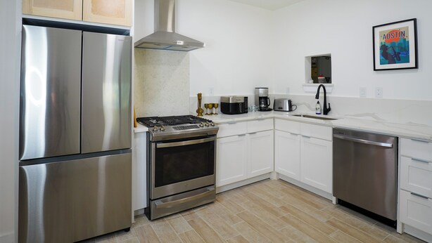 A modern kitchen with stainless steel appliances, white cabinetry, and a tiled floor. - Fully Renovated 4-Bedroom, 3-Bath Home in the Heart of Austin's Attractions (Austin)