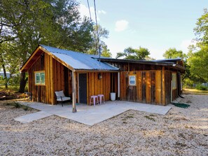 A wooden cabin with a porch, two windows, and a door.