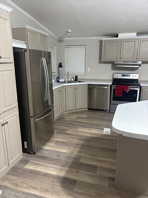 A kitchen with a stainless steel refrigerator, a stove, and a dishwasher. -  3-bedroom 2 full bath mobile home in nice quiet area 10 minutes from town (Richwood)