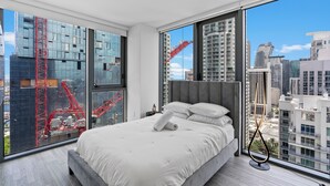 Un dormitorio moderno con una cama grande, vistas a la ciudad y una grúa fuera de la ventana.
