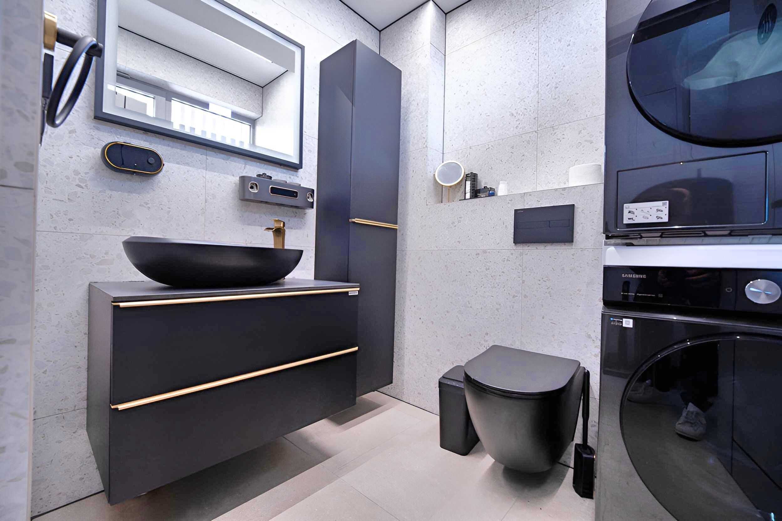 Un baño moderno con un lavabo negro, un espejo, un inodoro y una lavadora.