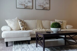 A living room with a sofa, a coffee table, and a small potted plant.