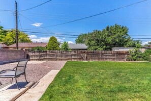 A backyard with a wooden fence, a bench, and a grassy lawn. - A New, Modern & Spacious 6-bedroom house in peaceful Pueblo (Pueblo)