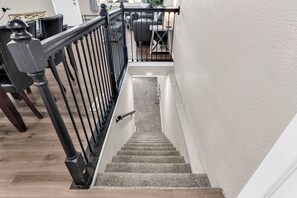 A staircase with a black railing, carpeted steps, and a white wall. - A New, Modern & Spacious 6-bedroom house in peaceful Pueblo (Pueblo)