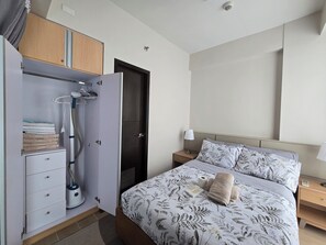 A bedroom with a bed, a nightstand, a wardrobe, and a door. - Mactan Infinity Pool View|Near Airport & Beach (Lapu-Lapu)