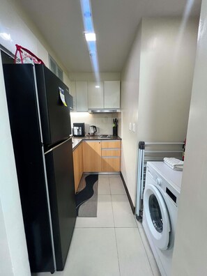 A compact kitchen with a refrigerator, microwave, coffee maker, and a washing machine. - Mactan Infinity Pool View|Near Airport & Beach (Lapu-Lapu)