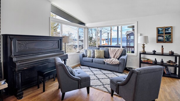 A living room with a piano, a sofa, two armchairs, a rug, and a view of the outside. - Seattle Skyline & Lake Retreat | 3Bd/3Ba (Seattle)