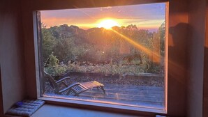 Una finestra con vista su un tramonto su un paesaggio boschivo.