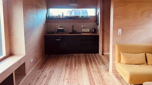 Una cucina compatta con mobili in legno, un piano cottura integrato e una finestra vista edificio.