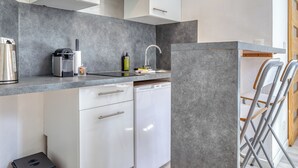 Una cocina compacta equipada con lavavajillas, cafetera y un lavabo con grifo.