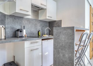 A compact kitchen with a built-in dishwasher, a coffee maker, and a sink with a faucet. - Shelter 2 - joli studio proche gare (Rouen)