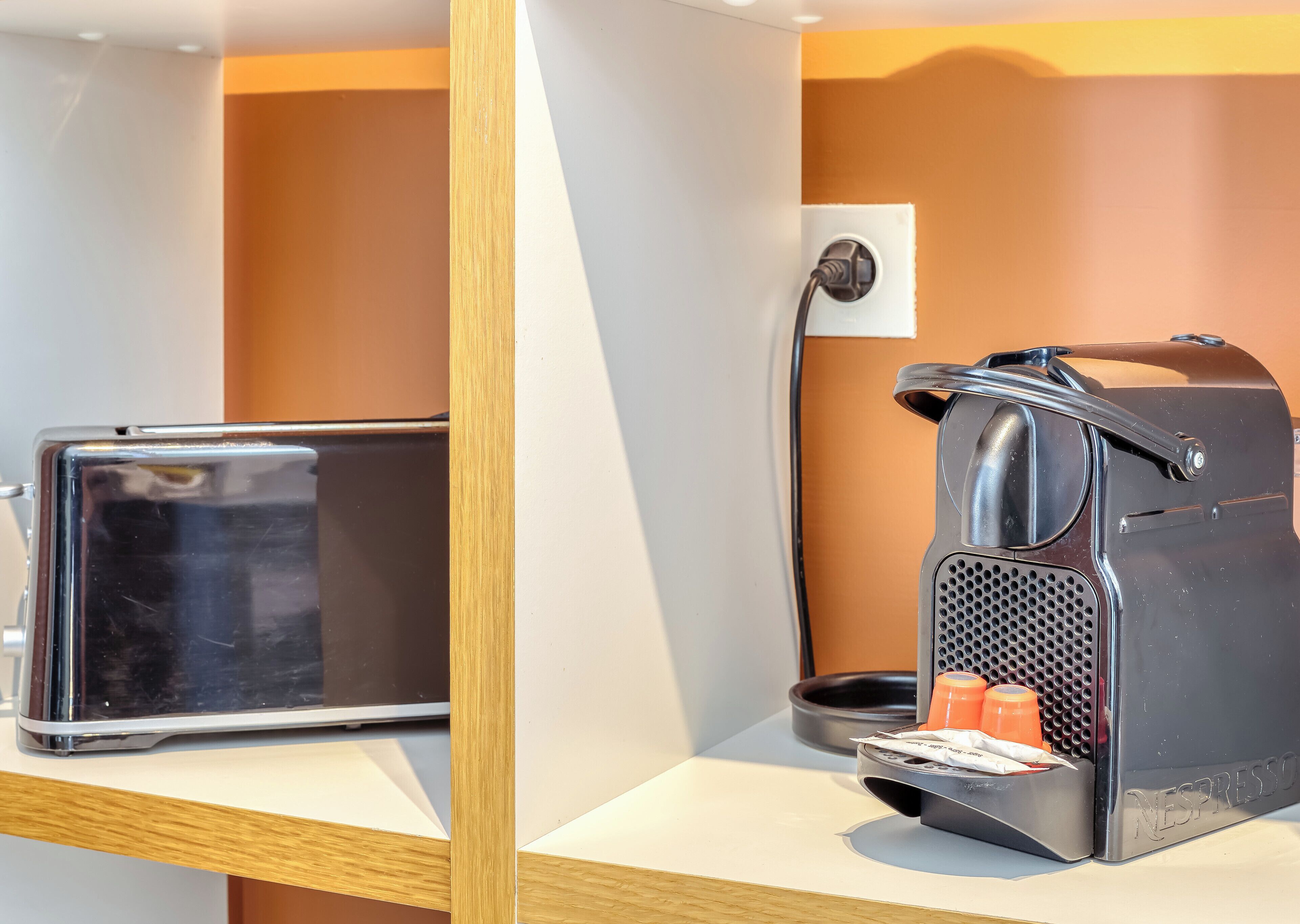 Uma máquina de café e um tablet sobre uma superfície branca com moldura de madeira.