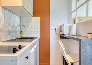 Une cuisine moderne équipée d’un évier, d’un robinet et d’un four à micro-ondes.